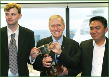 Tyler Fox and Melchor Inigo Raval hold the Kirby Cup, with the Hon Michael Kirby